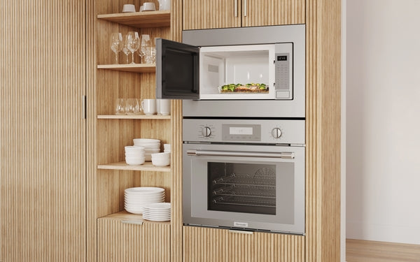 Built-in stainless steel microwave with left side door opening above matching built-in oven in modern kitchen cabinetry