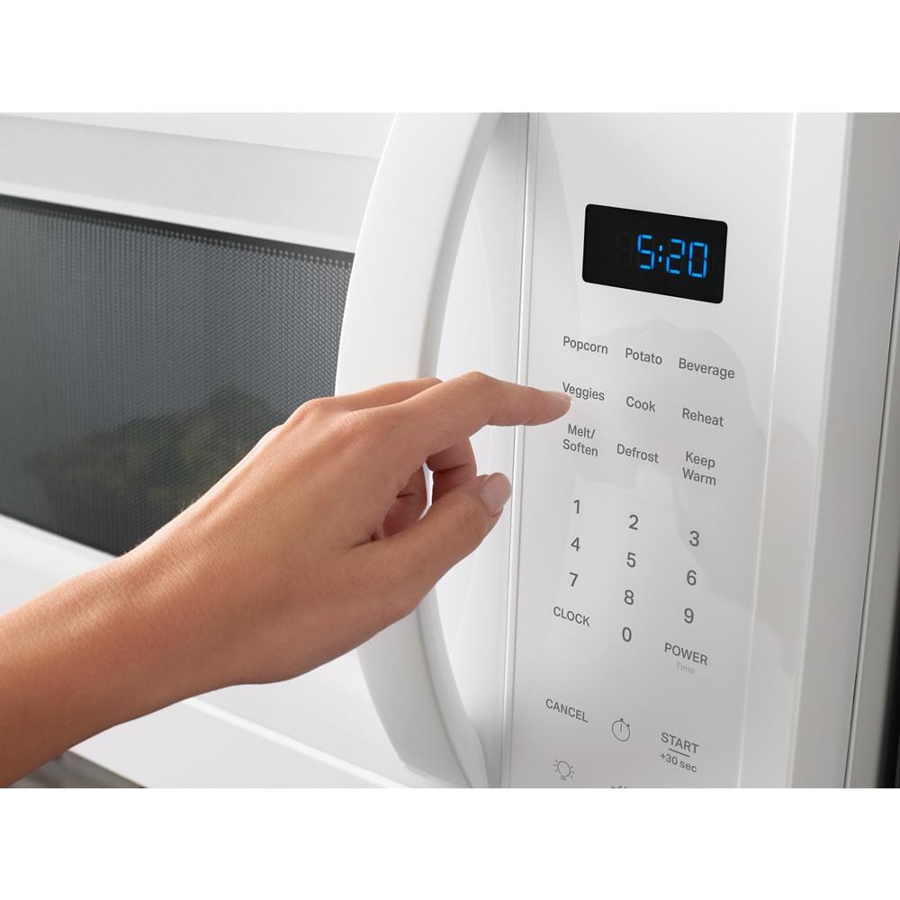 Hand pressing sensor cooking button on white over the range microwave control panel in kitchen appliances collection