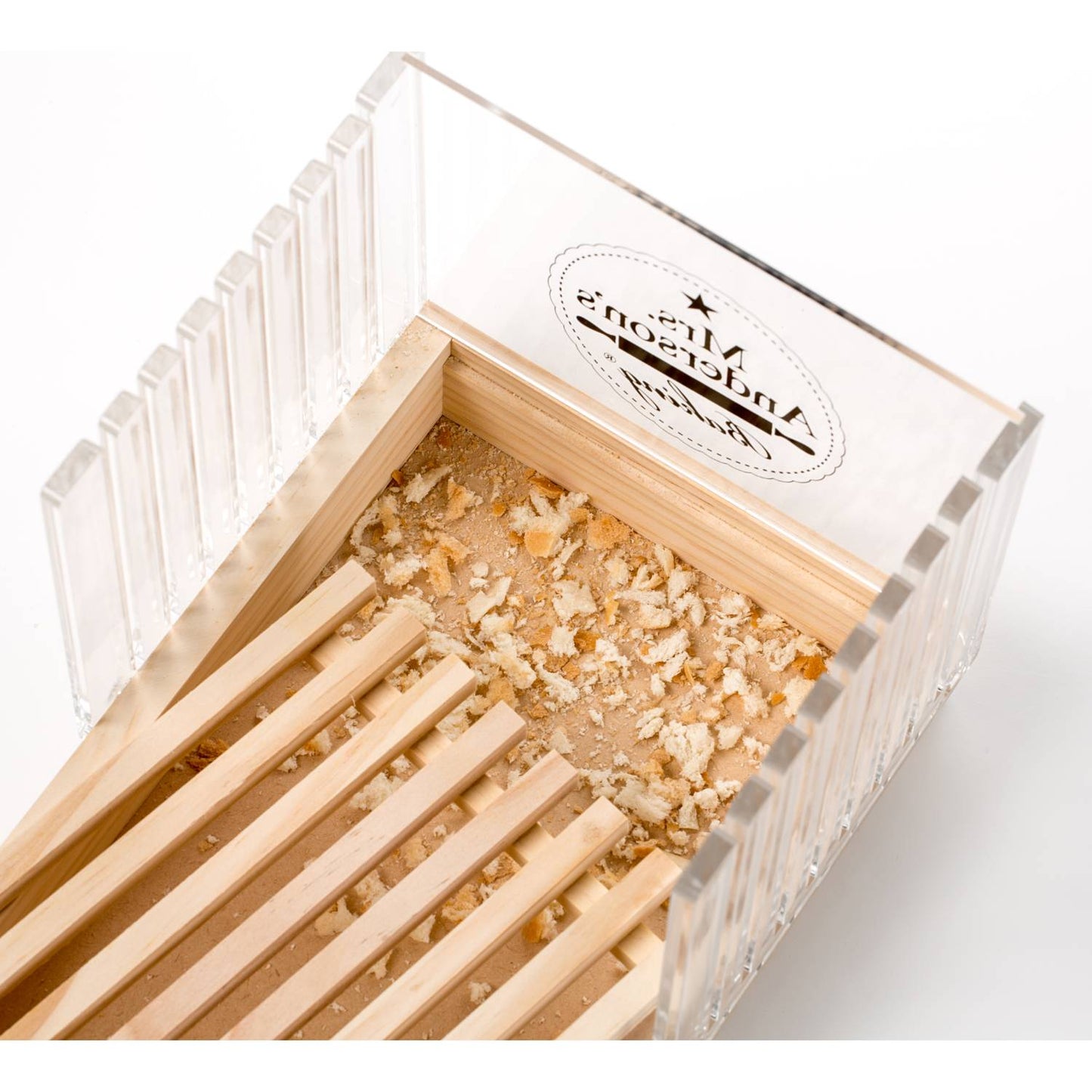 Bread slicing guide with wooden base and clear adjustable slots surrounded by bread crumbs in kitchenware collection