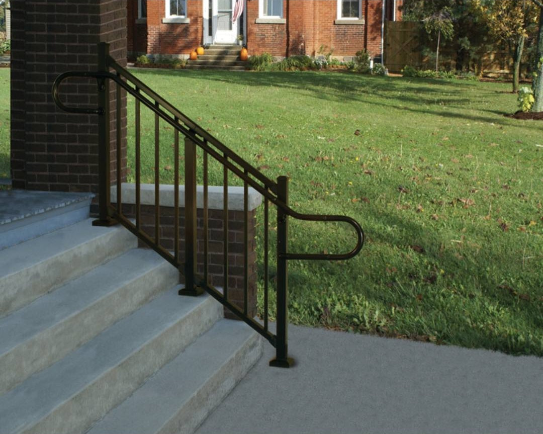 Black angled elbow fitting installed on ADA aluminum handrail along outdoor concrete steps for safety support