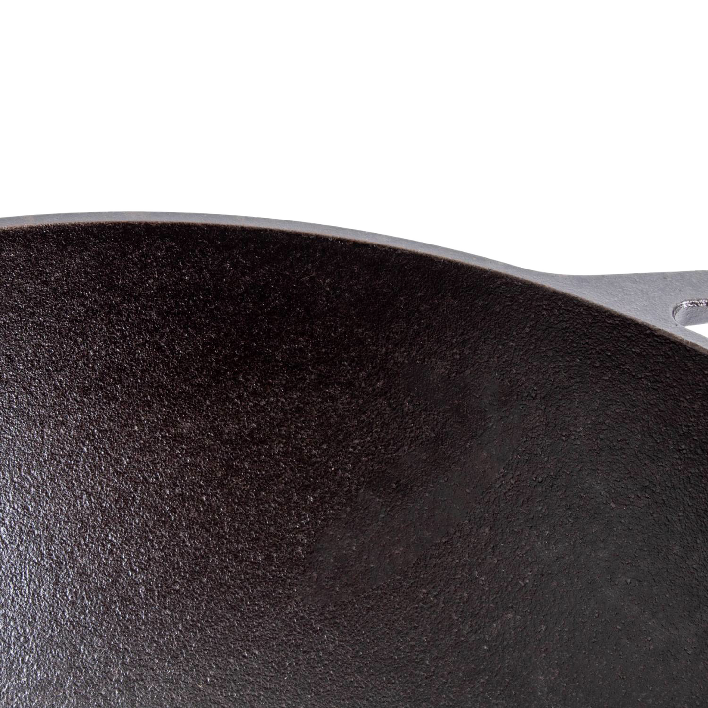 Part of a cast iron wok with wide base, showcasing its textured black cooking surface from Lodge Kitchenware collections.