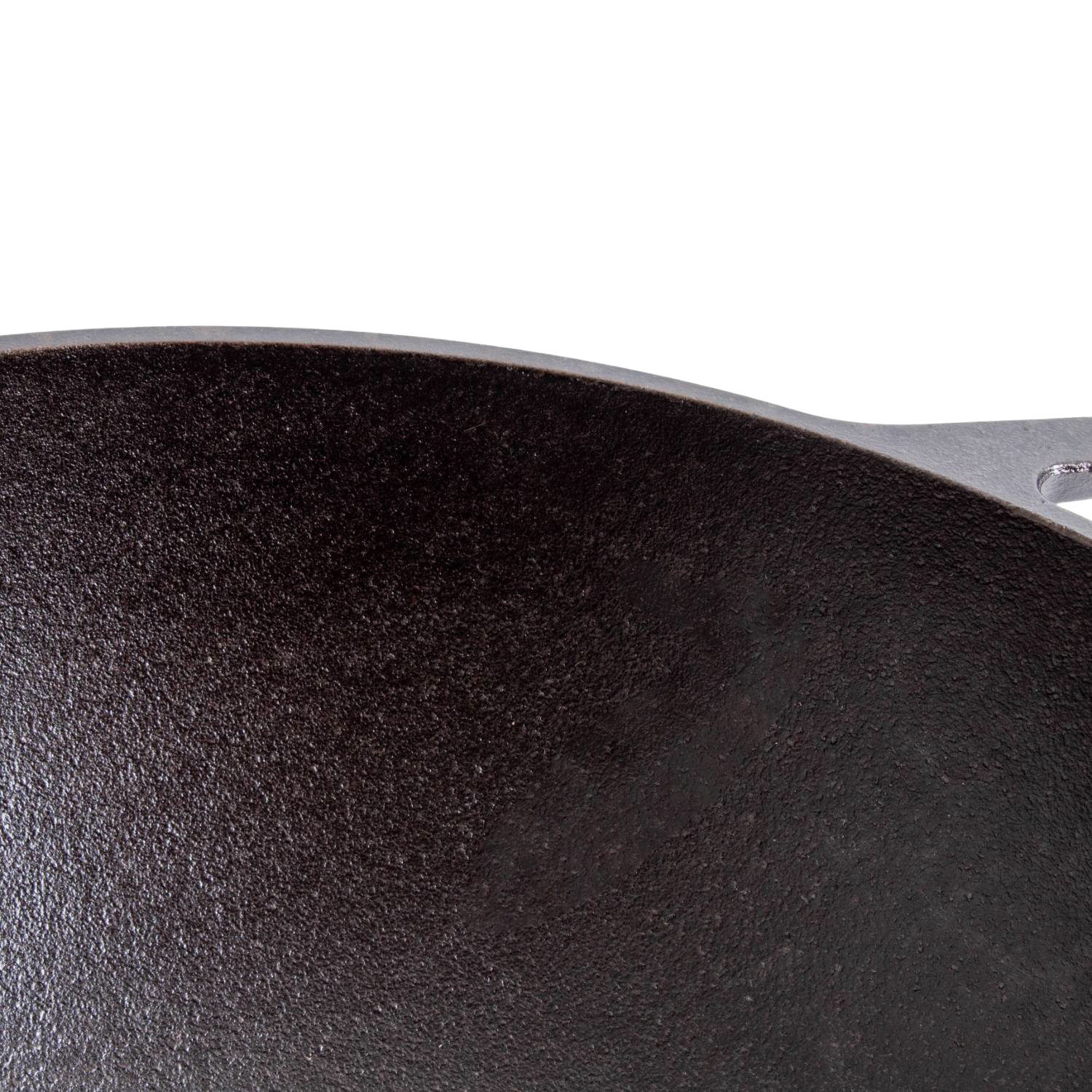Part of a cast iron wok with wide base, showcasing its textured black cooking surface from Lodge Kitchenware collections.