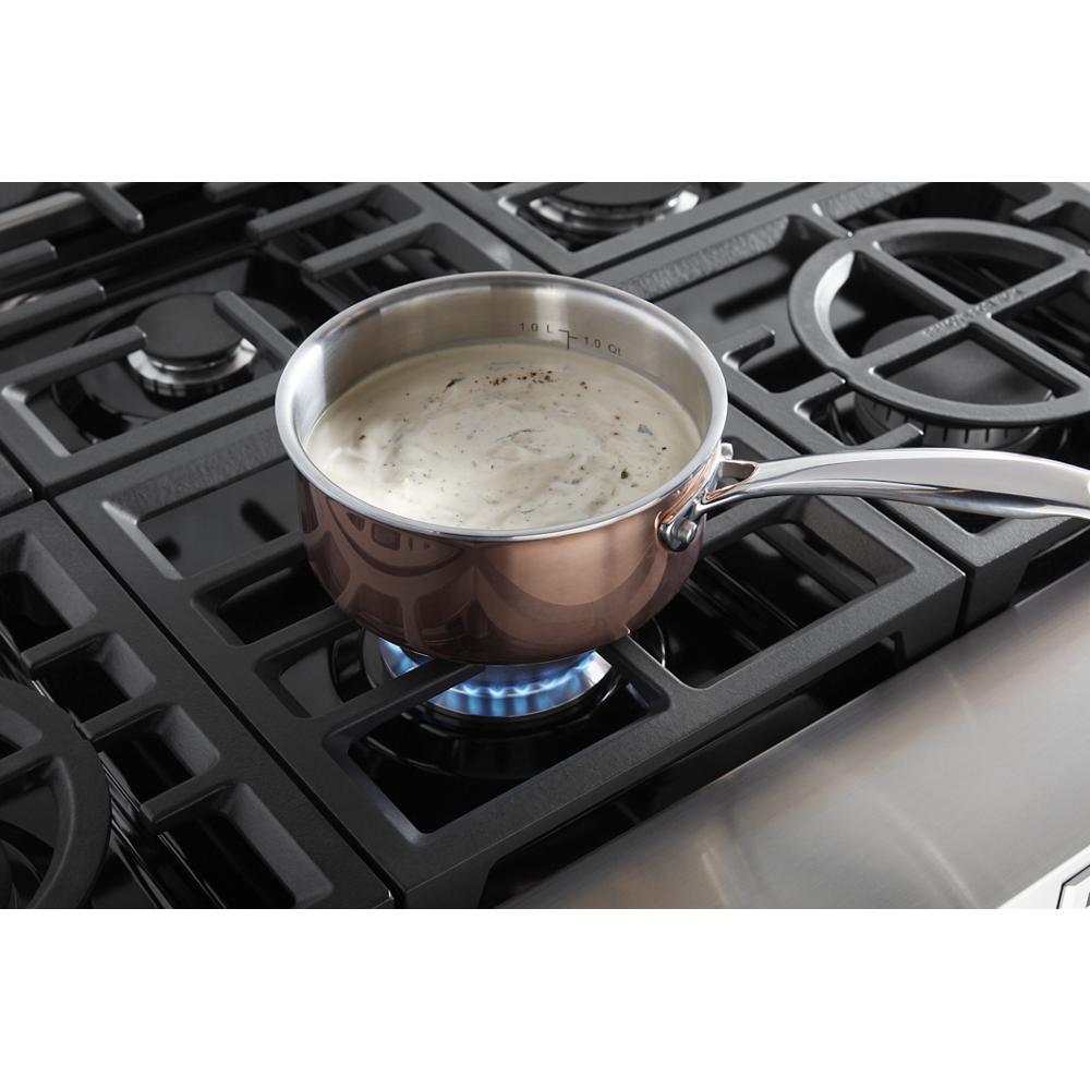 Copper saucepan with creamy sauce simmering on black KitchenAid cooktop burner in kitchenware and appliances collection
