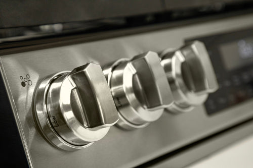 Close-up of stainless steel control knobs on slide-in gas range in kitchen appliances and ranges collection