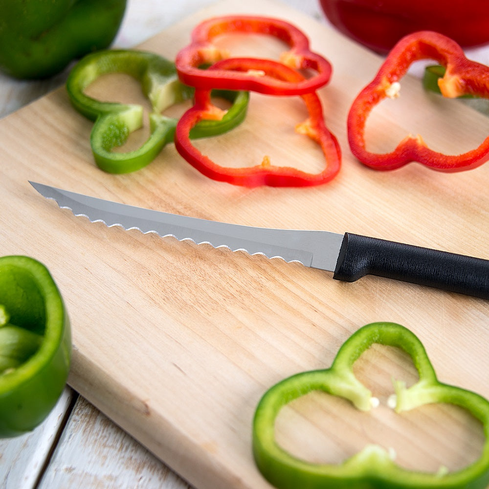 Rada Tomato Slicer with black handle and serrated blade slicing red and green bell peppers on wooden board in kitchenware collection