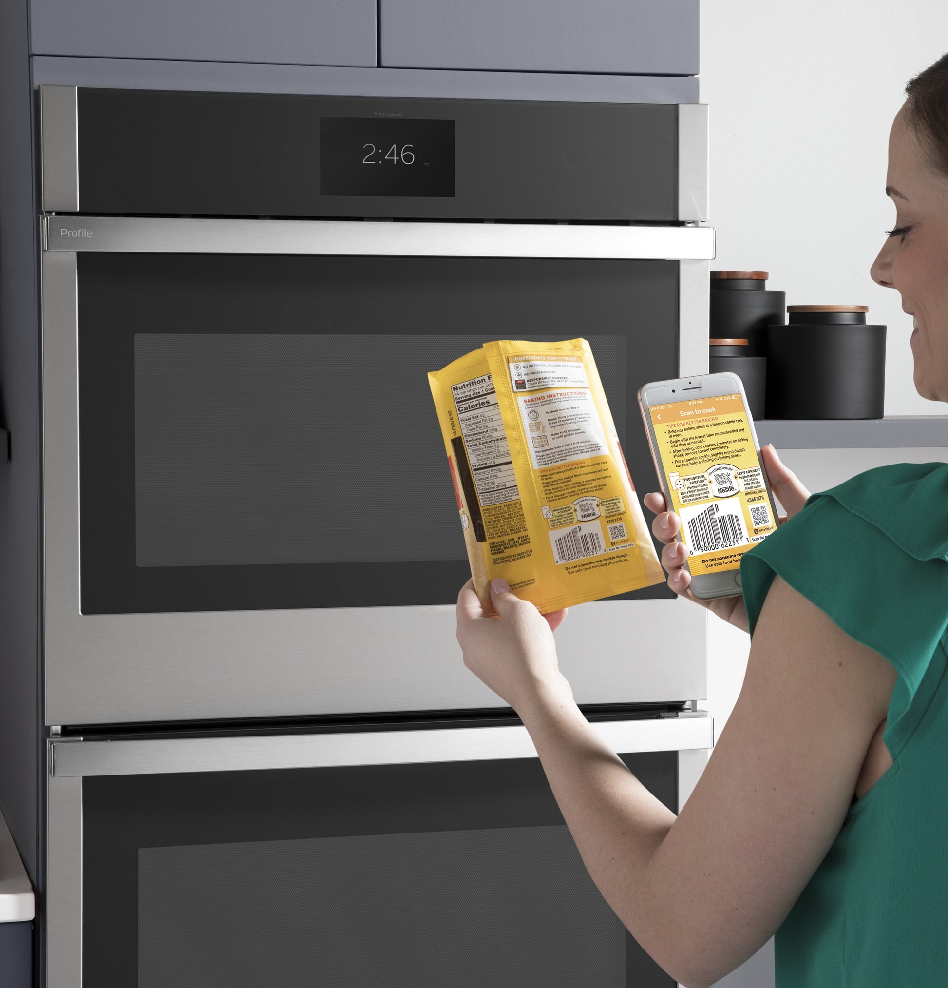 Person scanning a food package barcode with smartphone app near a stainless steel built-in double wall oven