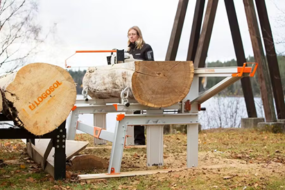 Metal frame chain sawmill with three log supports cutting large timber in outdoor home improvement setting