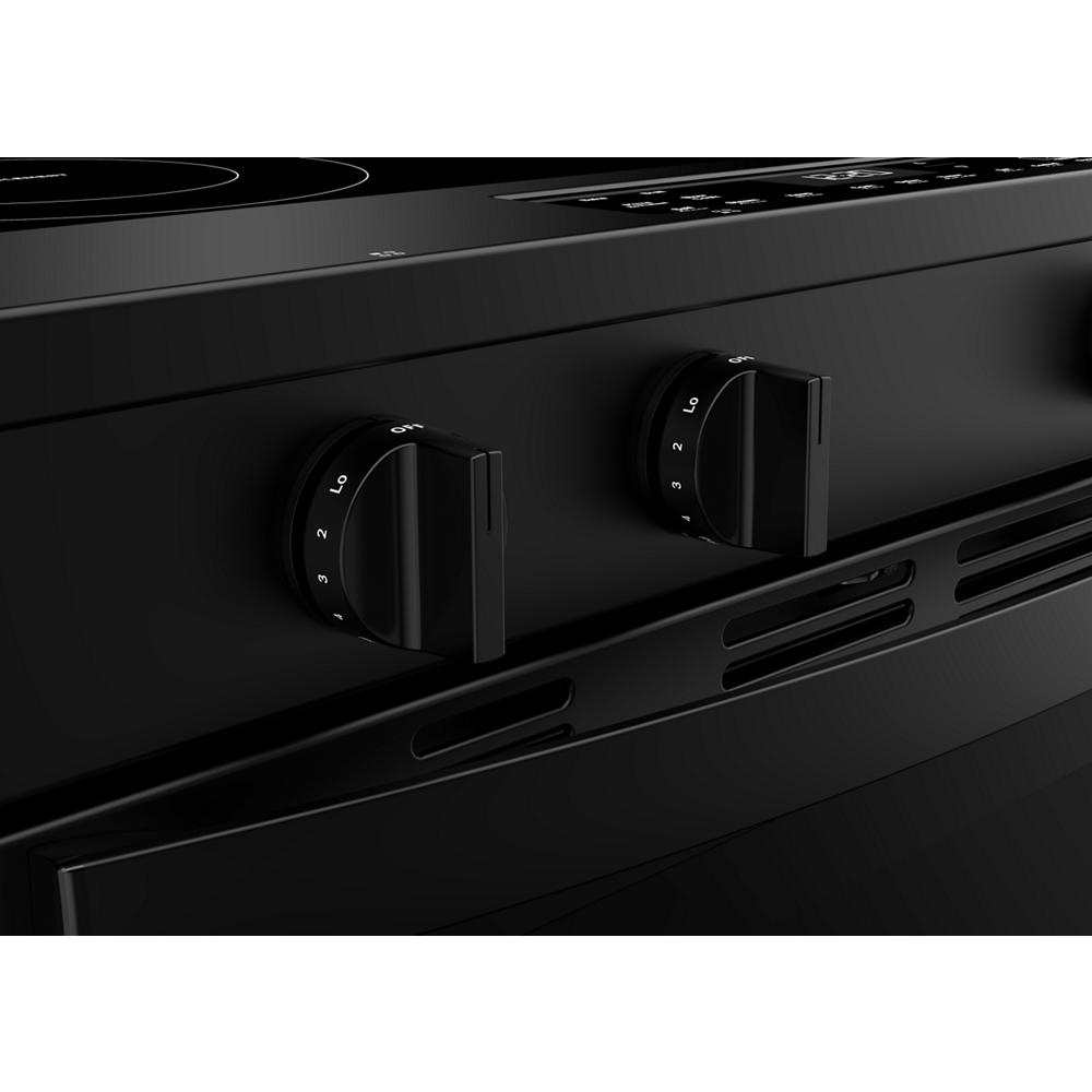 Close-up of black electric range control knobs and vent panel in a modern kitchen appliance setting