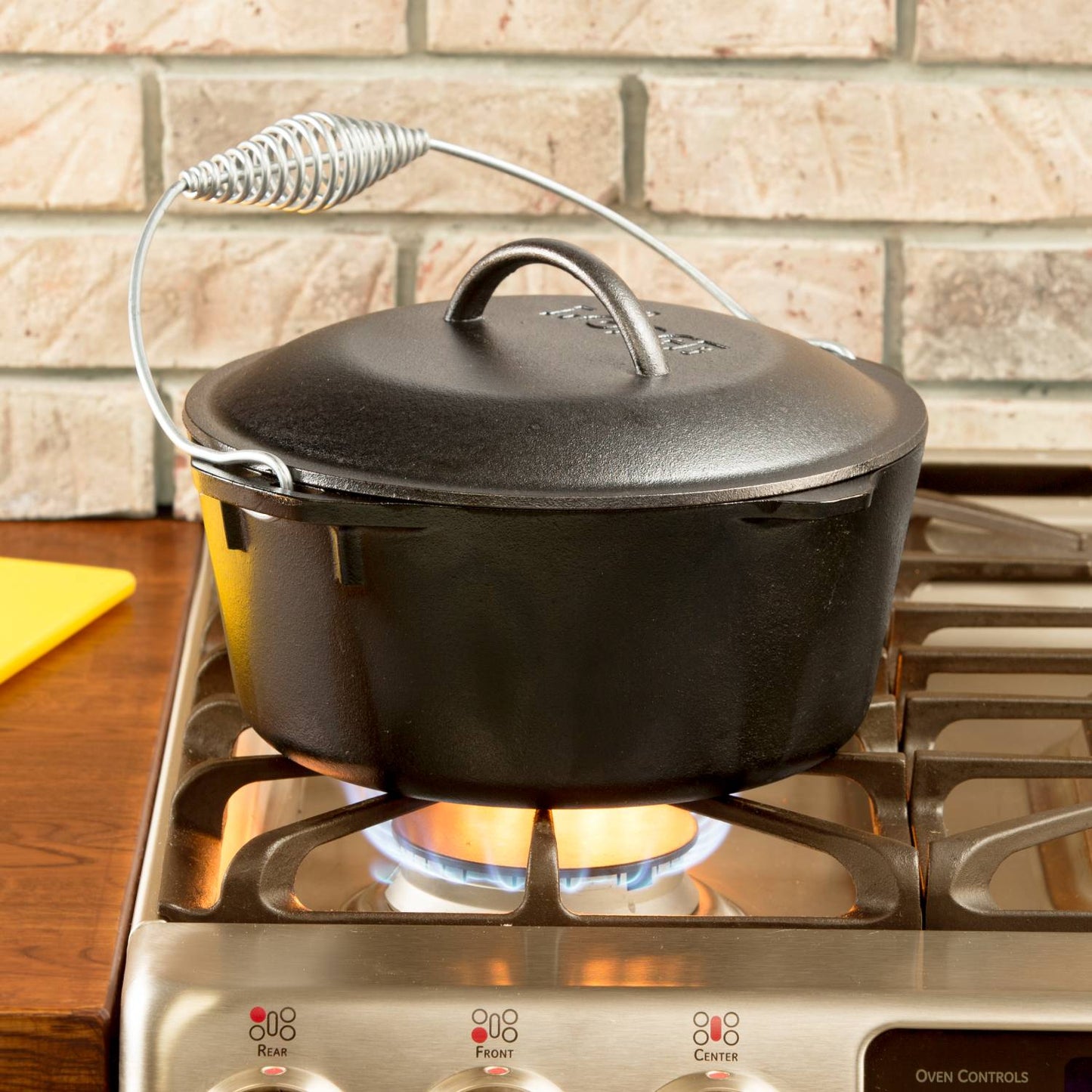 Black cast iron Dutch oven with coil bail handle cooking on gas stove burner in kitchenware under $100 collection