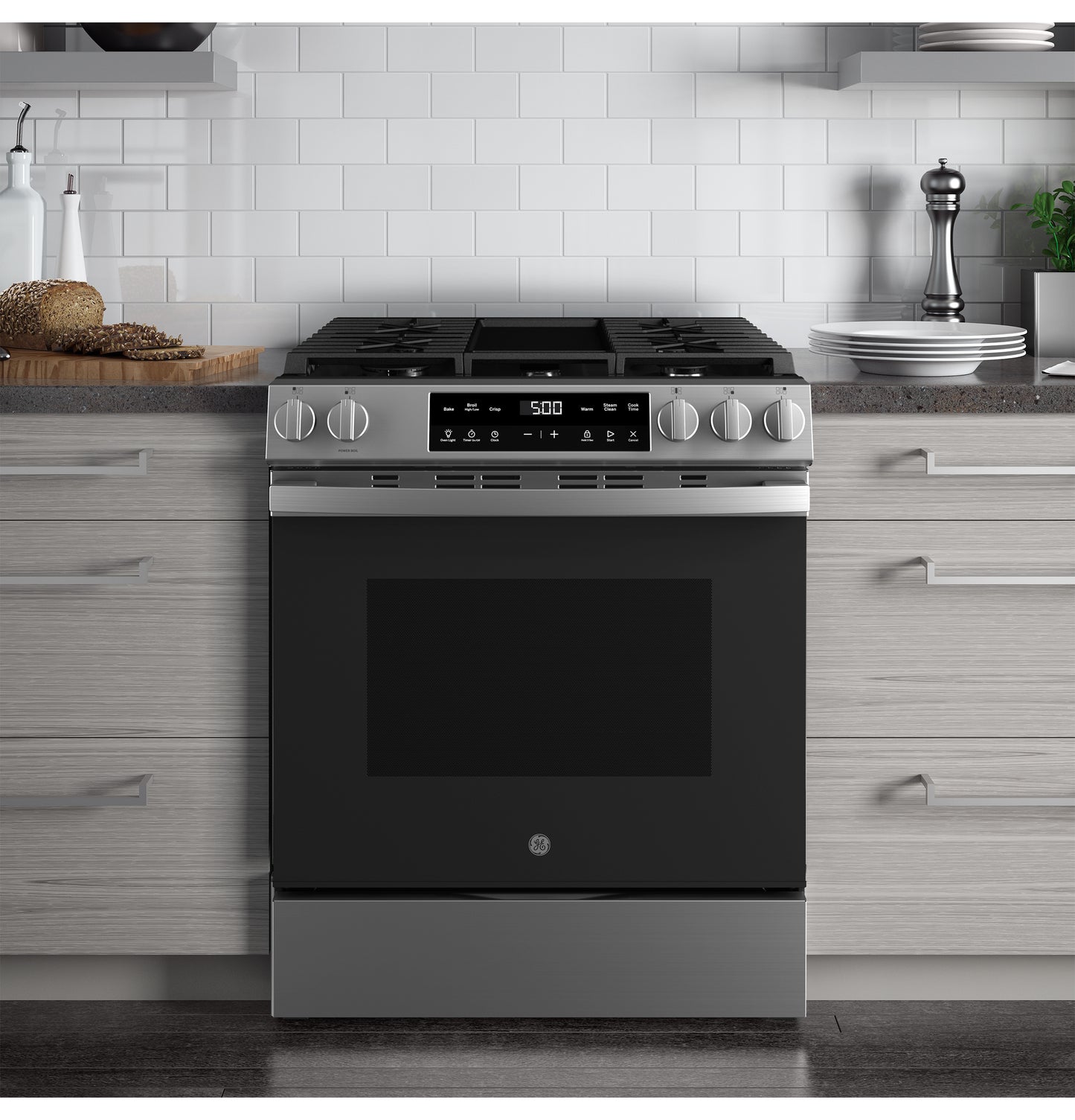 Slide-in stainless steel front control gas range with digital display and knob controls in modern kitchen setting