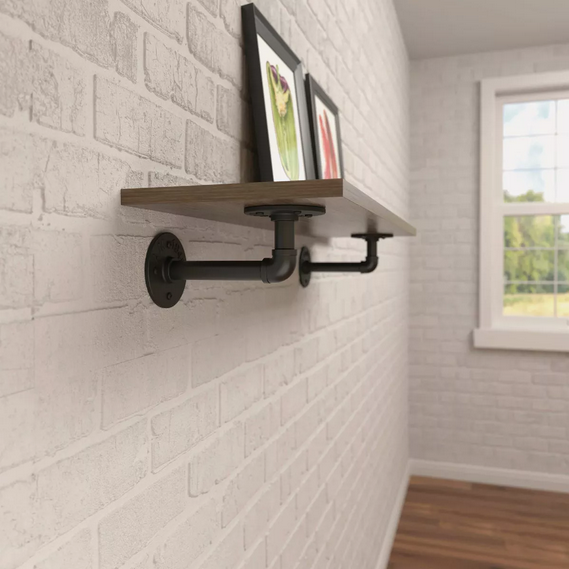 Black elbow pipe brackets supporting wooden floating shelf on white brick wall in home improvement setting