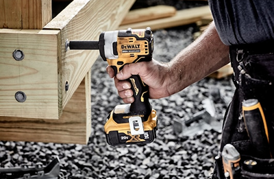 Cordless impact wrench in yellow and black being used to fasten large wood beams for home improvement projects
