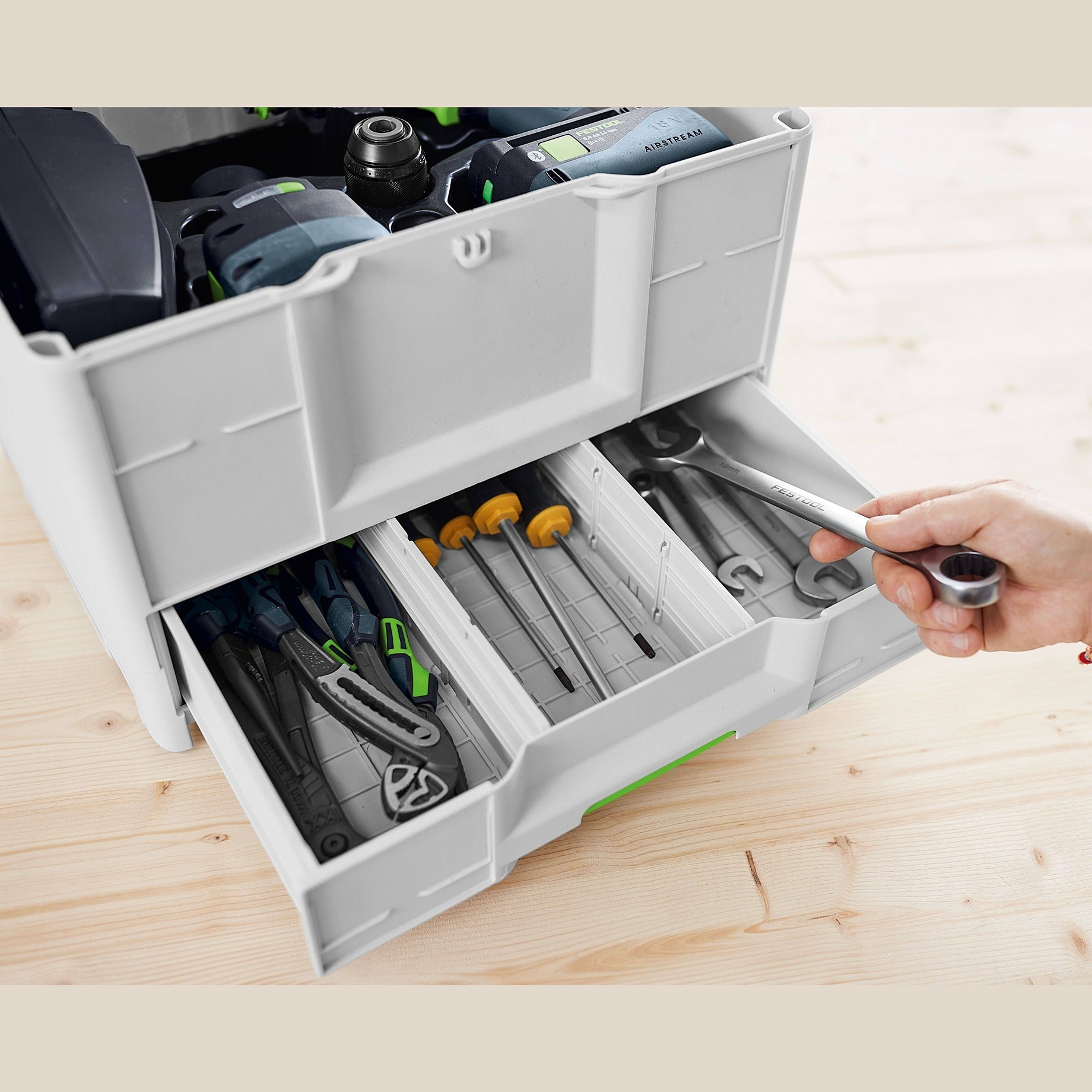 Gray and green Festool storage system drawer open with organized hand tools and accessories on wooden surface