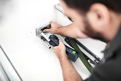 Person adjusting a Festool plunge base accessory on a cordless oscillating multi-tool for precision woodworking cuts