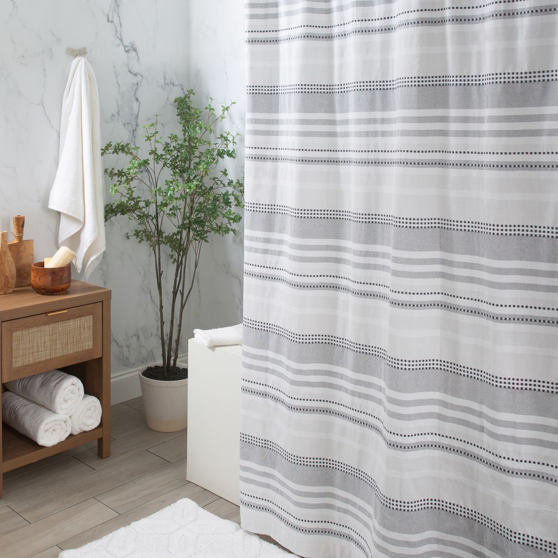 White and gray dot and stripe patterned cotton shower curtain in modern bathroom setting under $100 bath accessories