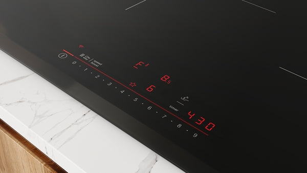 Close-up of sleek black induction cooktop control panel with red digital display on marble countertop for home improvement