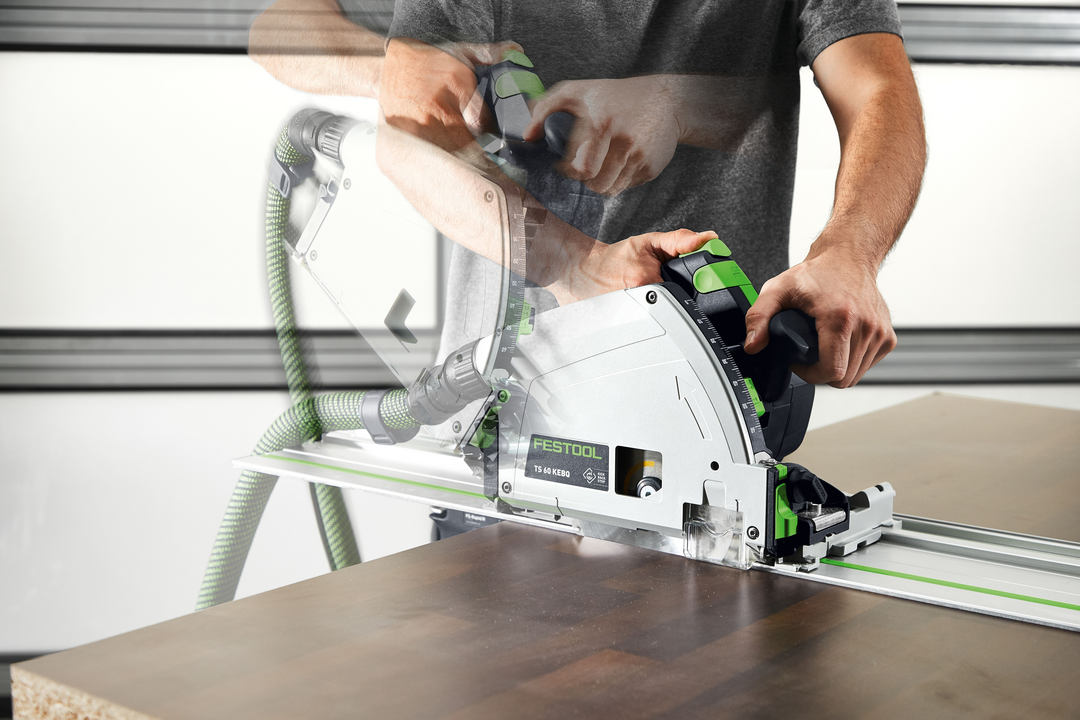 Man operating Festool plunge cut track saw on wood panel with dust extraction for home improvement tools