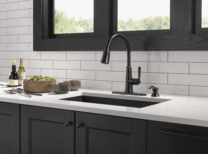 Matte black single-handle pull-down kitchen faucet with matching soap dispenser in modern kitchen setting