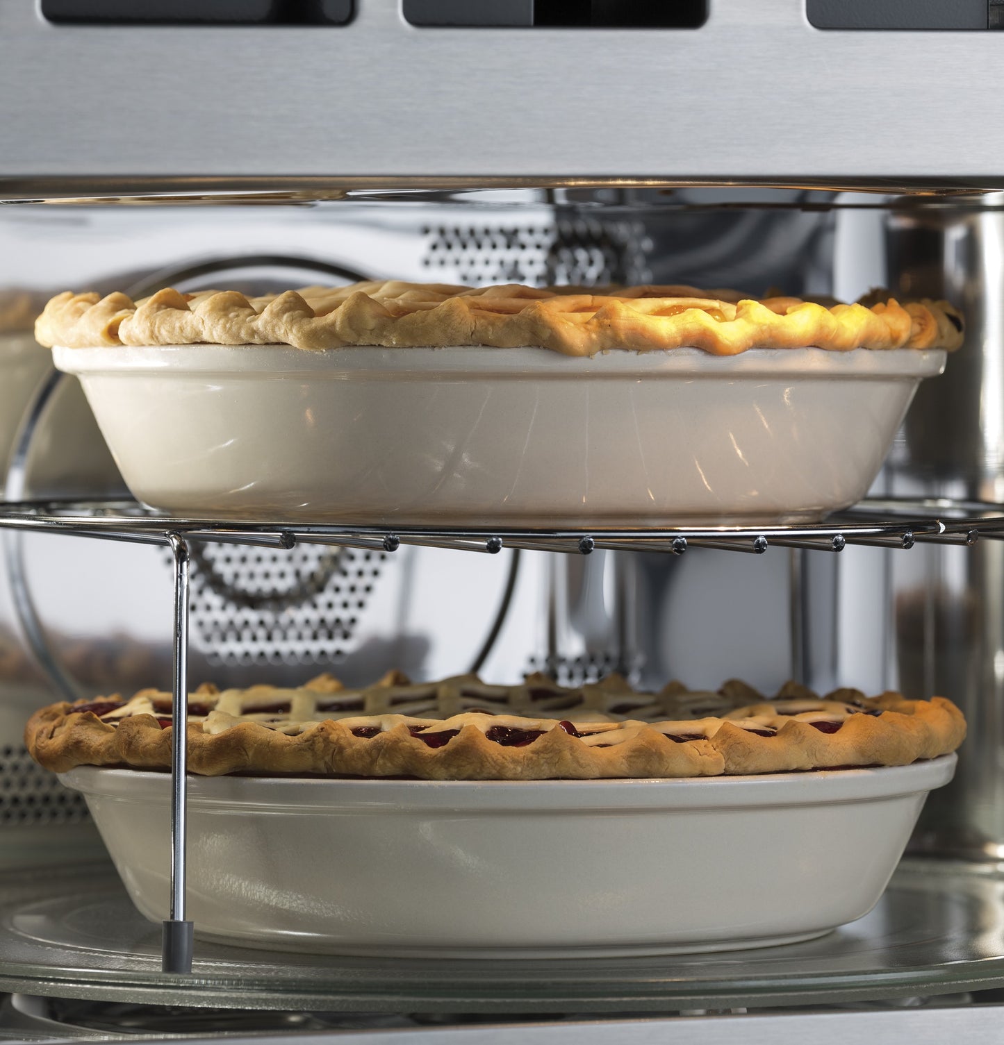Two ceramic pie dishes with baked pies inside a stainless steel built-in microwave convection oven in kitchen appliances collection