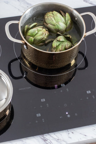 Induction cooktop with digital touch controls and a pot boiling artichokes for kitchen and home improvement use