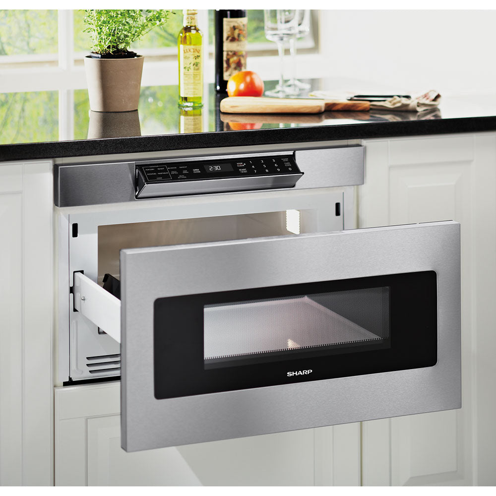 Open stainless steel microwave drawer with black tinted window and digital touch controls in modern kitchen setting