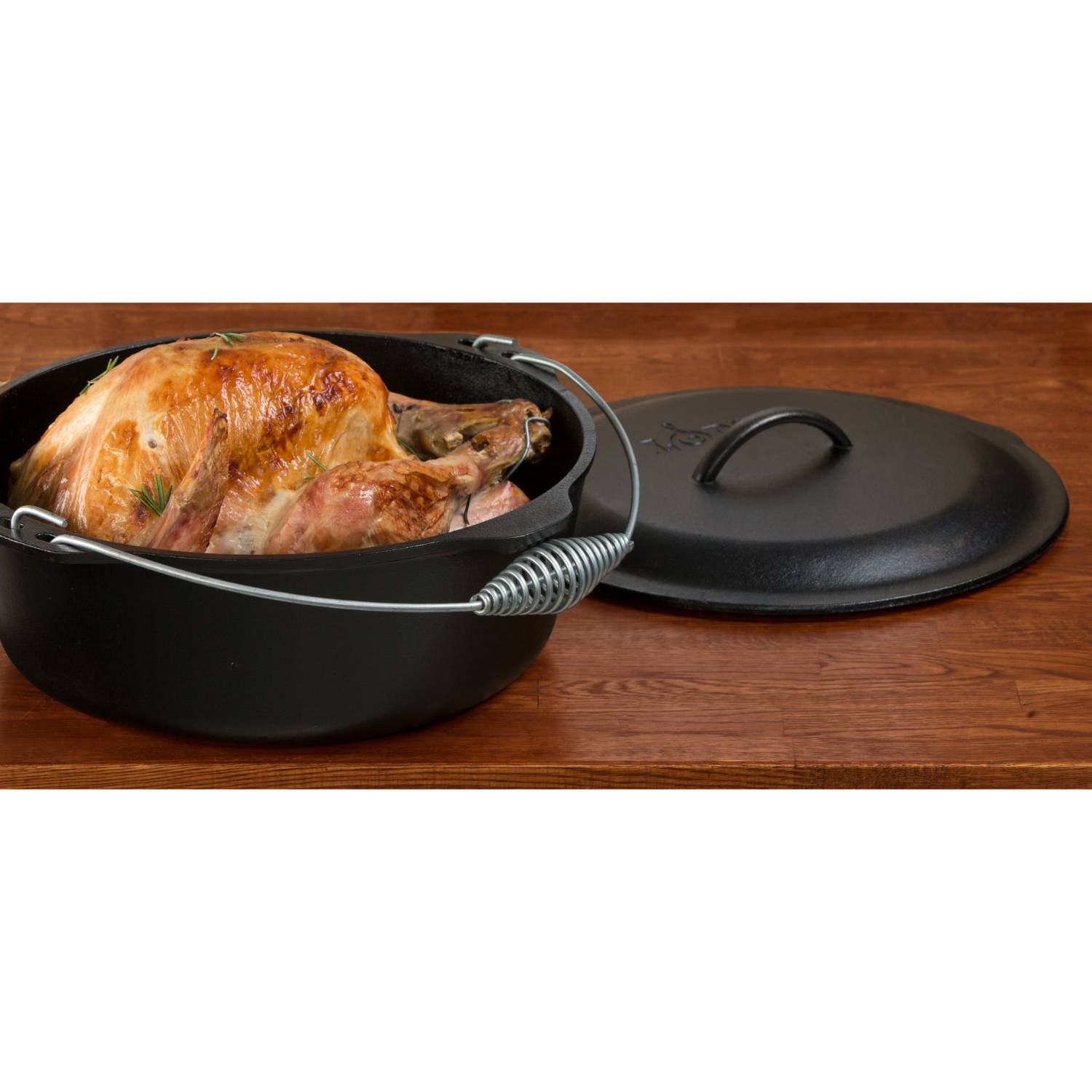 Classic cast iron Dutch oven with coil bail handle holding roasted chicken next to lid in kitchenware under $100 collection