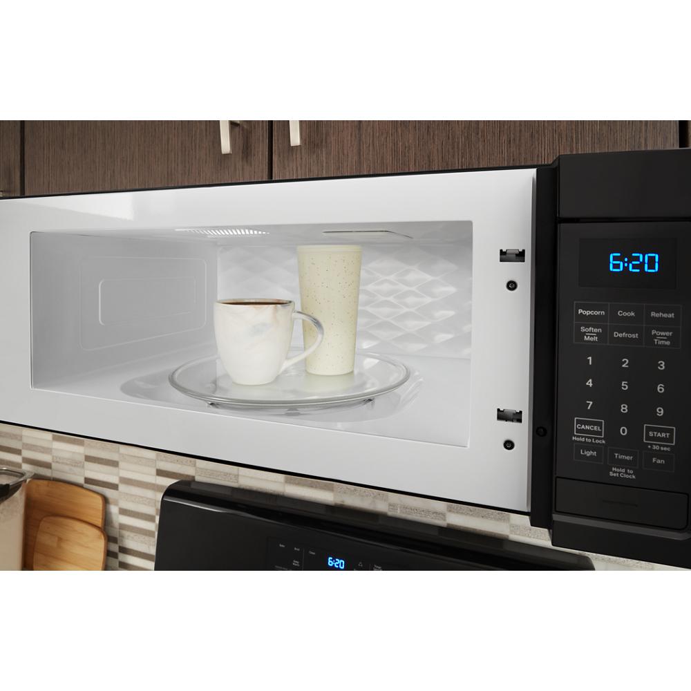 White low profile over-the-range microwave with digital keypad and two cups inside in modern kitchen setting