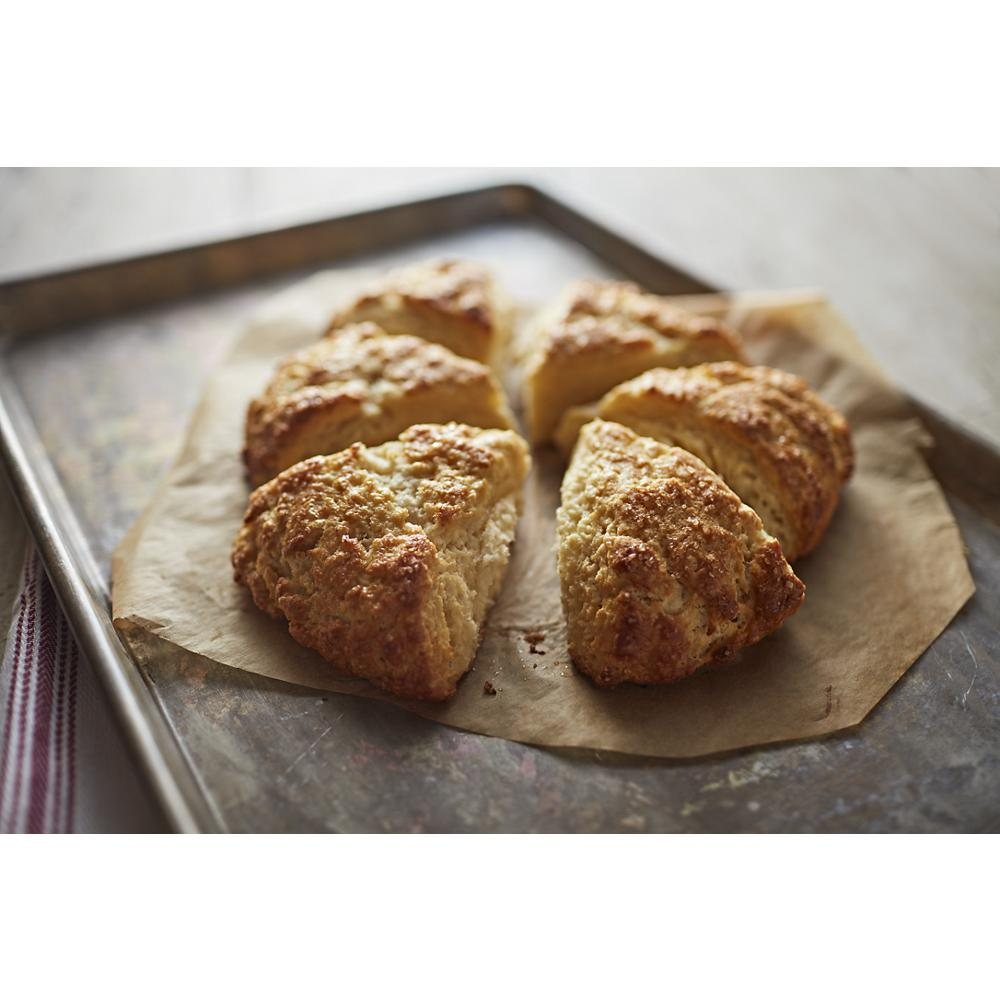 Golden brown freshly baked scones on parchment paper resting on a metal baking sheet from KitchenAid wall ovens collection