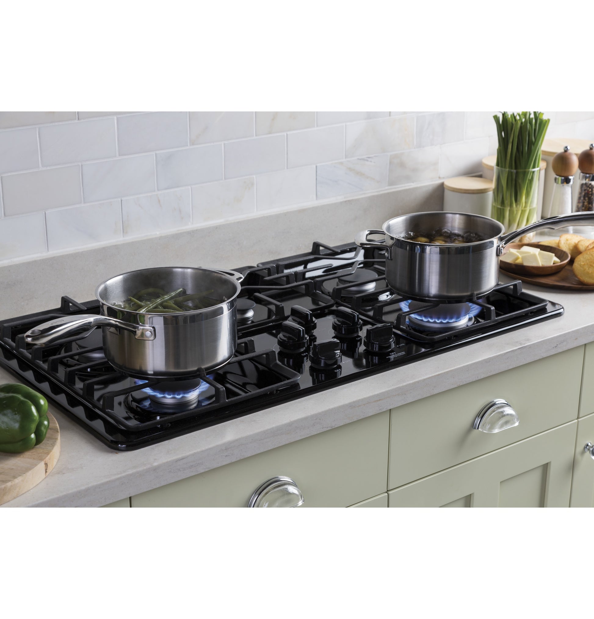 Black built-in gas cooktop with two stainless steel pots simmering on a modern kitchen countertop setting
