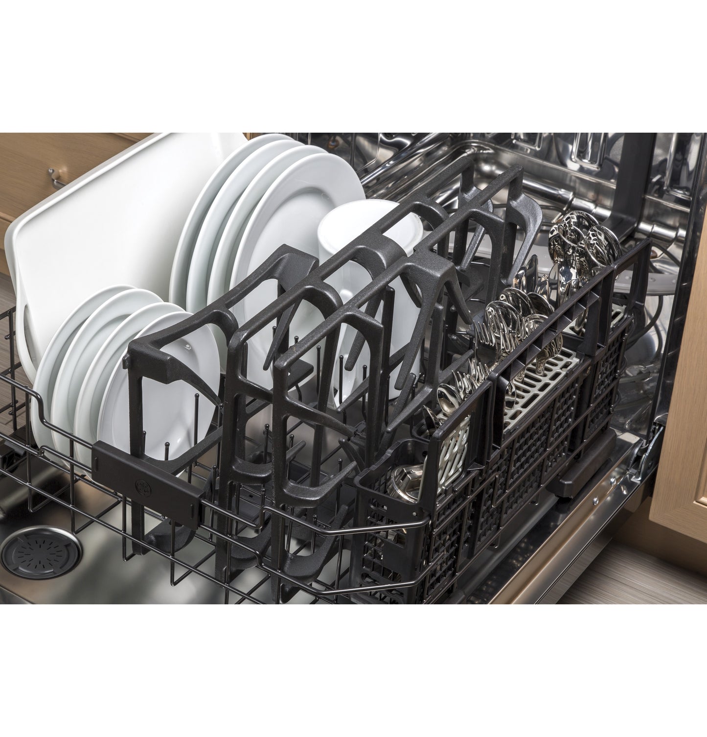Open dishwasher loaded with white plates, cups, and silver cutlery in kitchen appliances setting