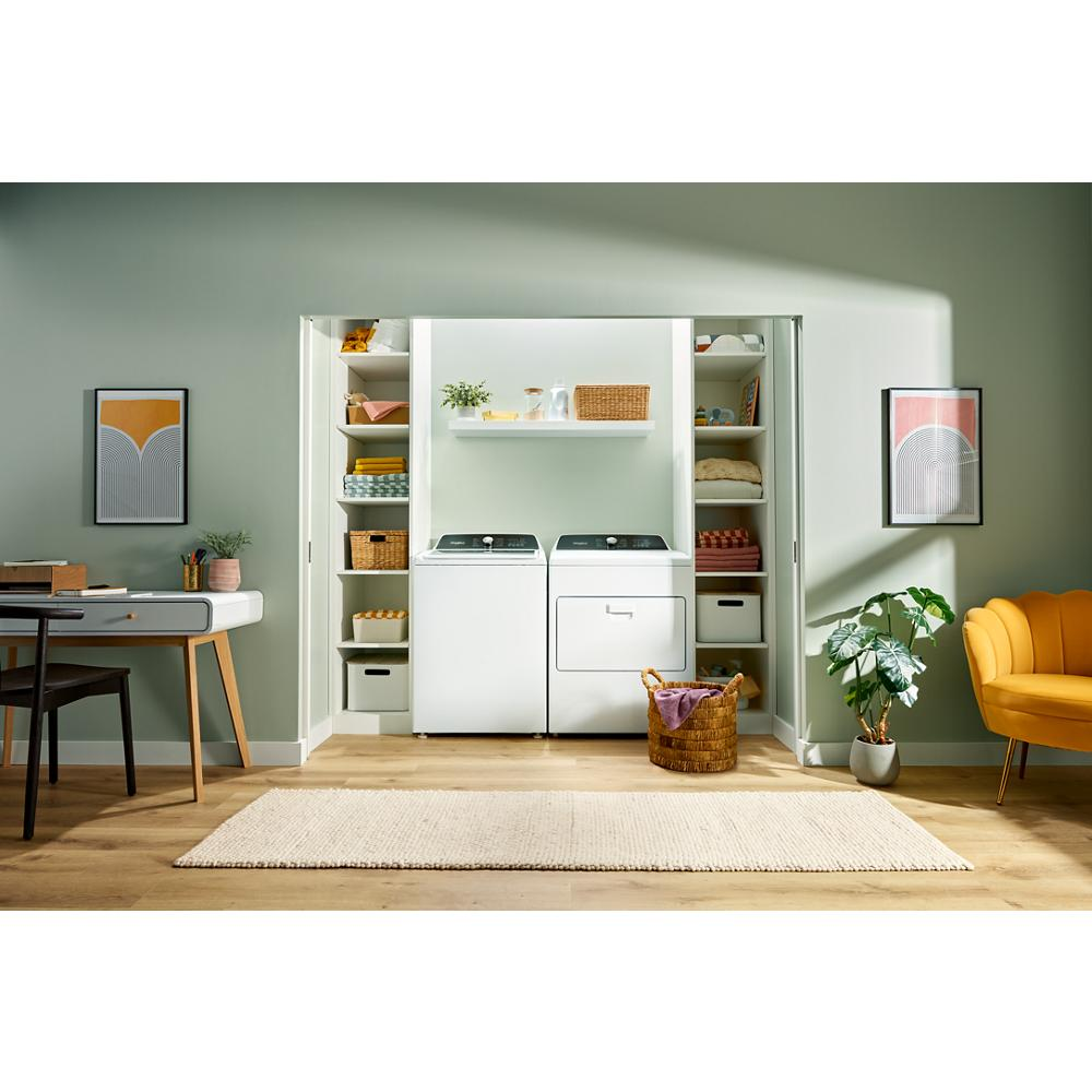 Laundry room with white top load washer and matching dryer surrounded by organized shelving and home decor