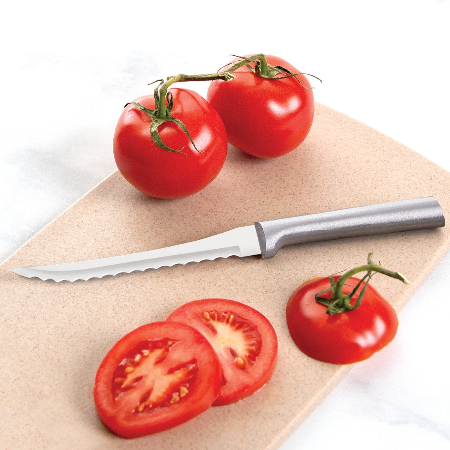 Serrated blade knife with a solid aluminum handle beside whole and sliced tomatoes on a beige cutting board, ideal for Kitchenware and Cooking Utensils collections.