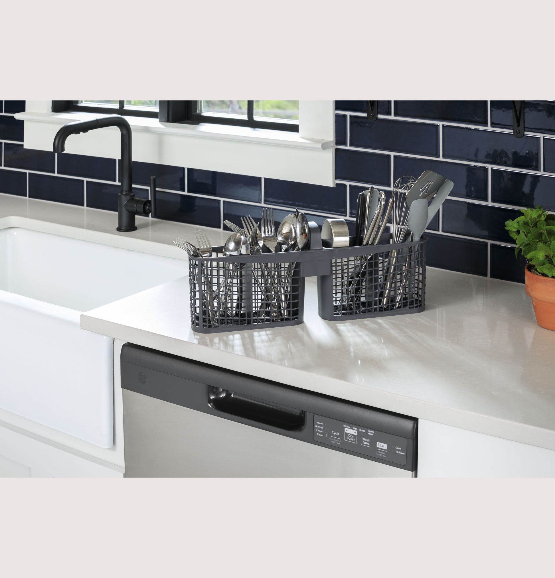 Stainless steel dishwasher with front controls under white countertop next to farmhouse sink and black faucet in modern kitchen