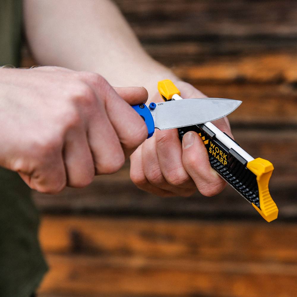Person using a black and yellow Work Sharp Pocket Knife Sharpener on a folding knife blade for home improvement tasks