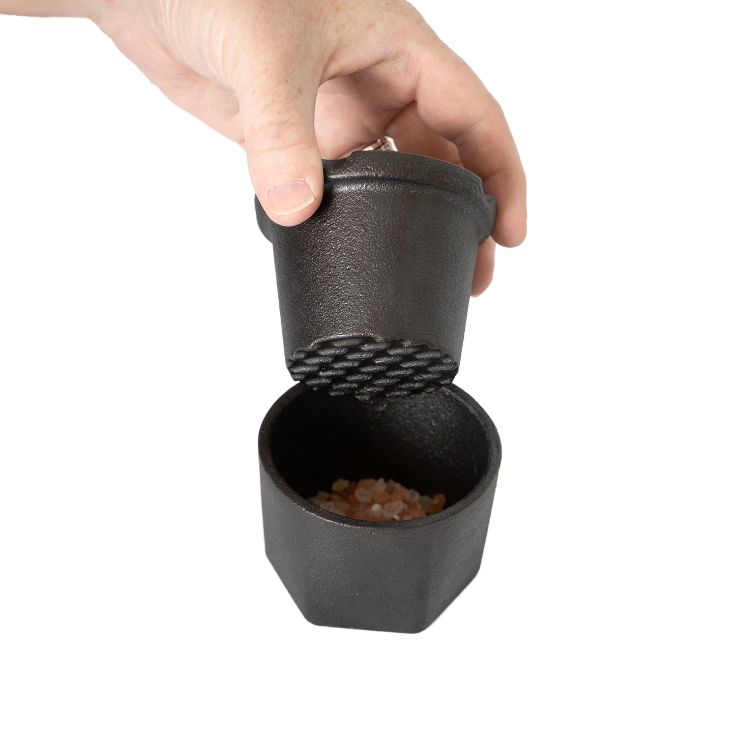 Hand holding cast iron spice grinder with pink Himalayan salt inside for kitchen gadgets under $50 collection