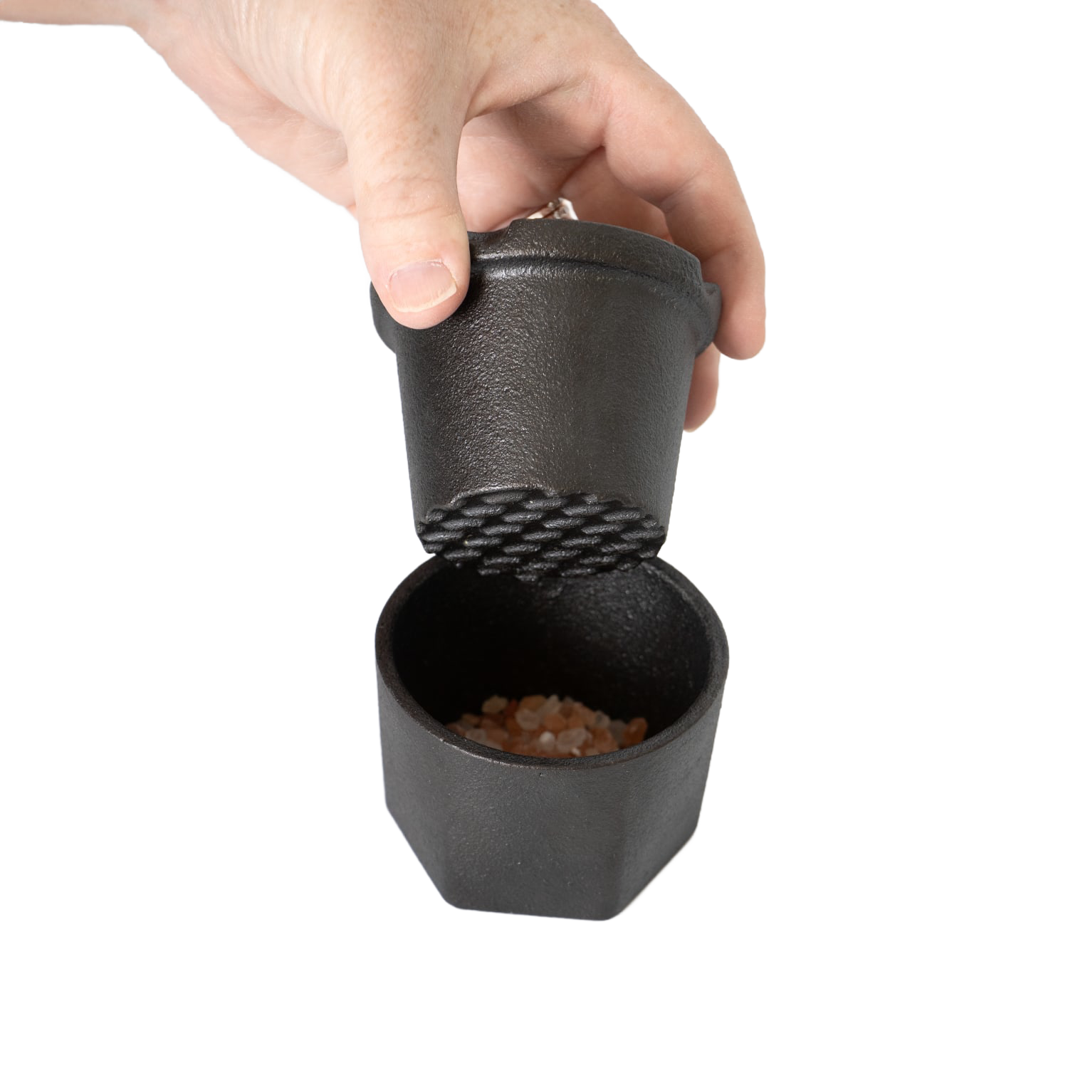 Hand holding cast iron spice grinder with pink Himalayan salt inside for kitchen gadgets under $50 collection