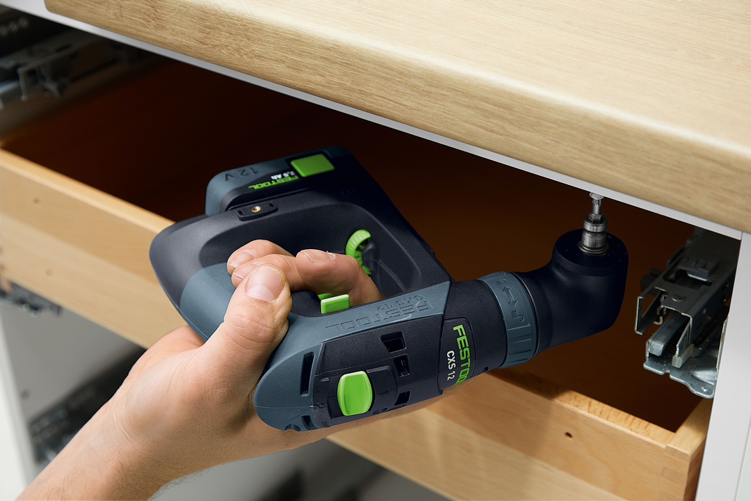 Hand using Festool cordless drill with angled attachment to install hardware inside wooden drawer in woodworking setting