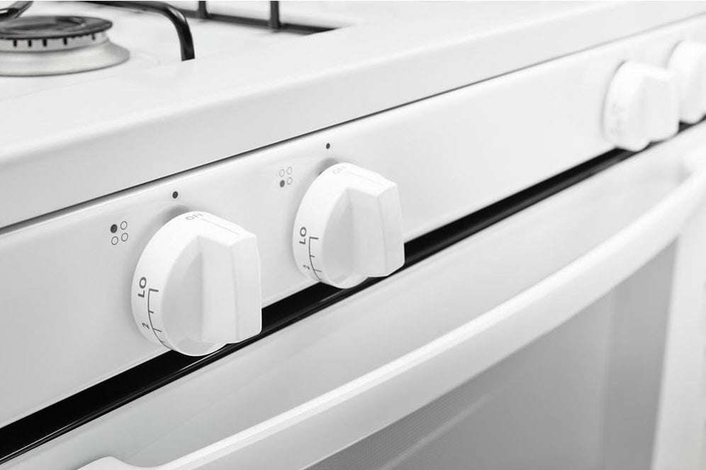 close-up of white gas range control knobs with temperature settings in kitchen and kitchenware appliances collection
