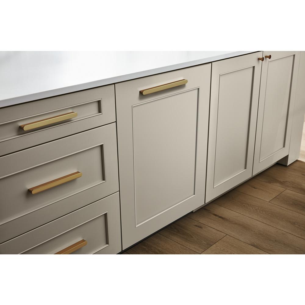 Built-in panel-ready dishwasher with custom door panel and brass handles integrated into beige kitchen cabinetry flooring in appliances category