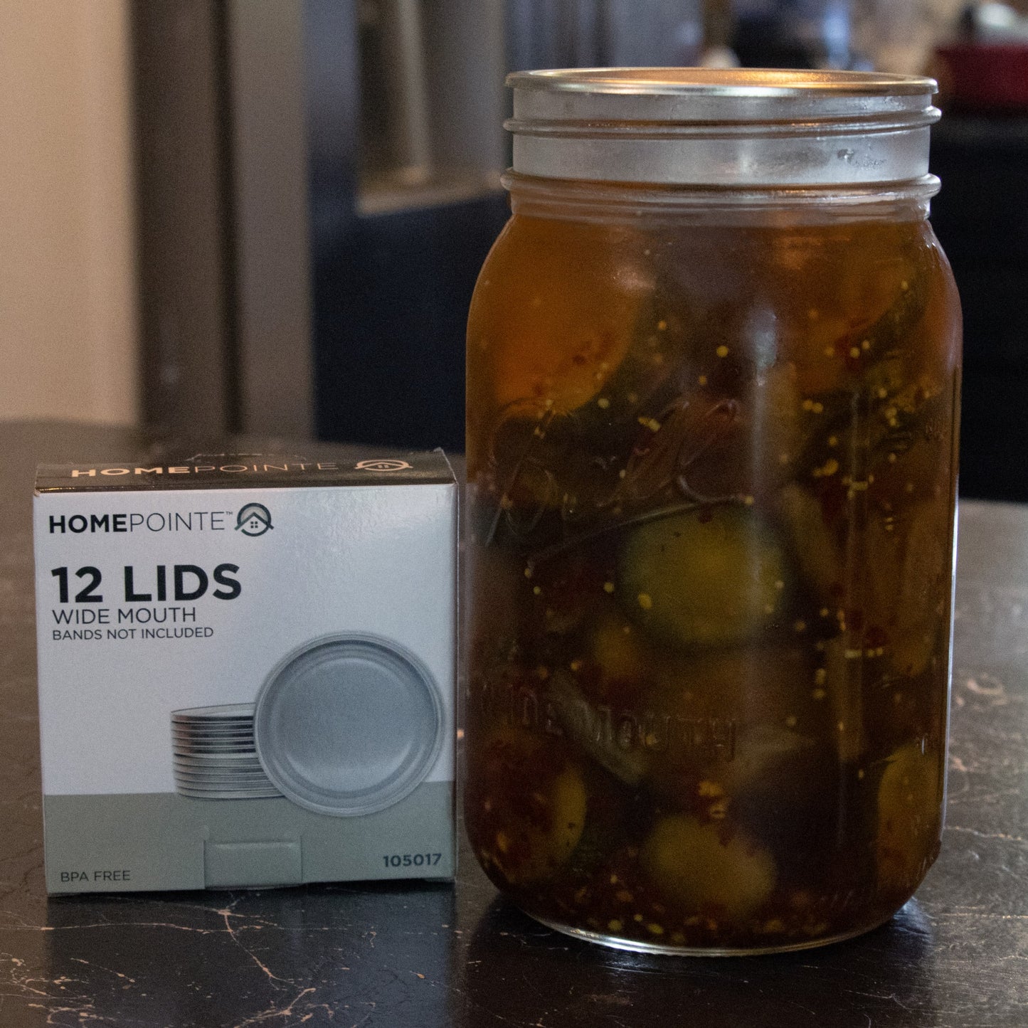 Glass jar of pickles sealed with silver wide-mouth lid next to box of 12 lids in kitchenware under $50 collection