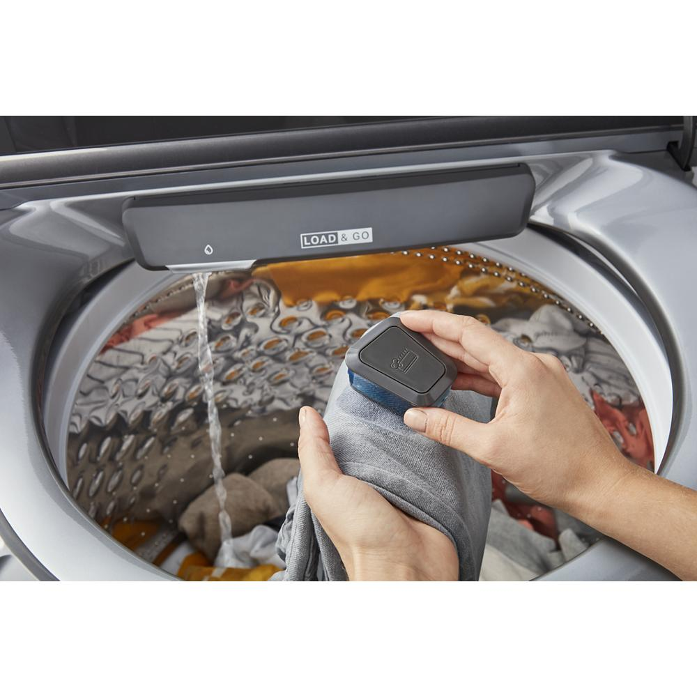 Hands loading detergent into a gray top load washer drum with water flowing, from Washers & Dryers collection