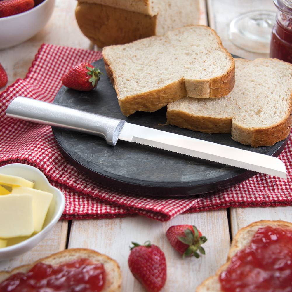 6-inch stainless steel bread knife with serrated edge and smooth handle on black board with sliced bread and strawberries