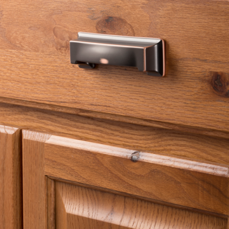 Oil-rubbed bronze finish studio cup pull mounted on natural wood cabinet drawer for home improvement projects