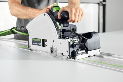 Plunge cut track saw with 75-inch guide rail cutting smoothly on white board for precise home improvement tasks