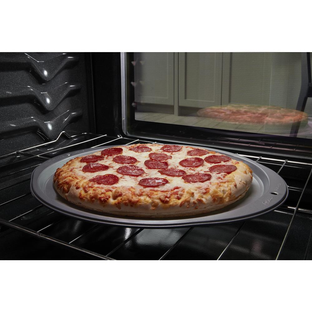 Frozen pepperoni pizza baking on a round tray inside an electric oven from the kitchen and appliances collection