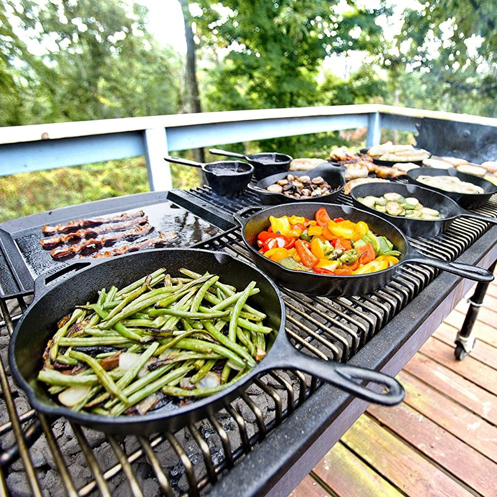 Cast iron cookware on outdoor grill cooking green beans, peppers, bacon, mushrooms, and zucchini in kitchenware collections under $100