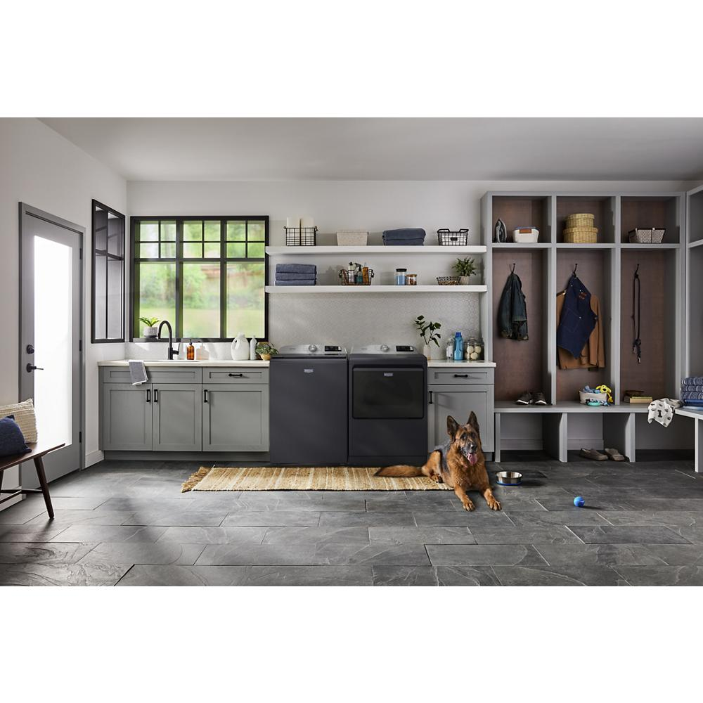 Modern laundry room with charcoal gray top load washer and dryer, storage shelves, and a German Shepherd on the floor