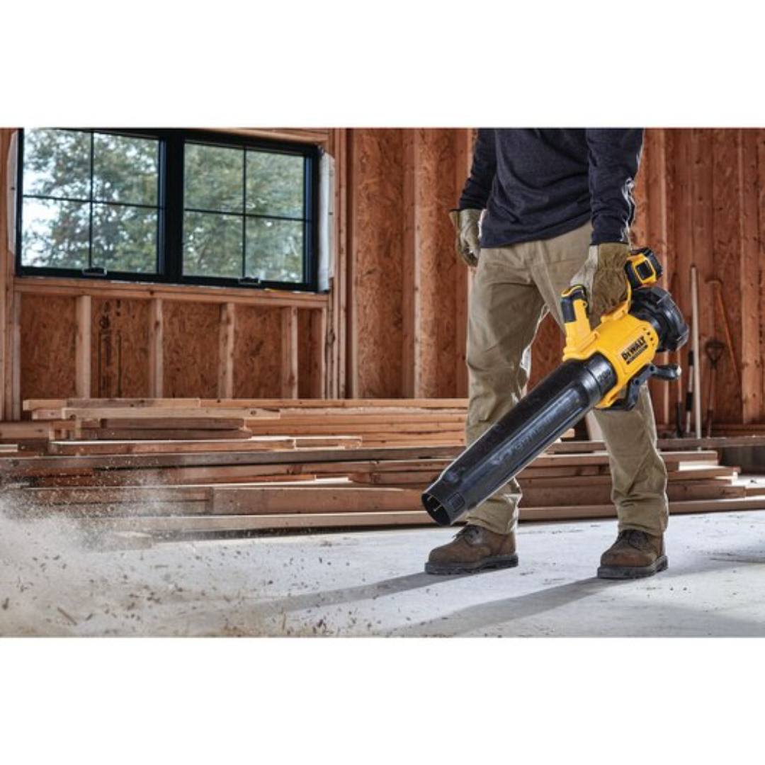 Person using DEWALT 20V MAX 5 Ah Lithium-Ion Brushless Handheld Blower (Tool Only) to clear debris inside unfinished wooden building