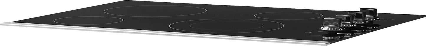 Black frameless 30-inch electric cooktop with four burners and front control knobs in kitchen setting