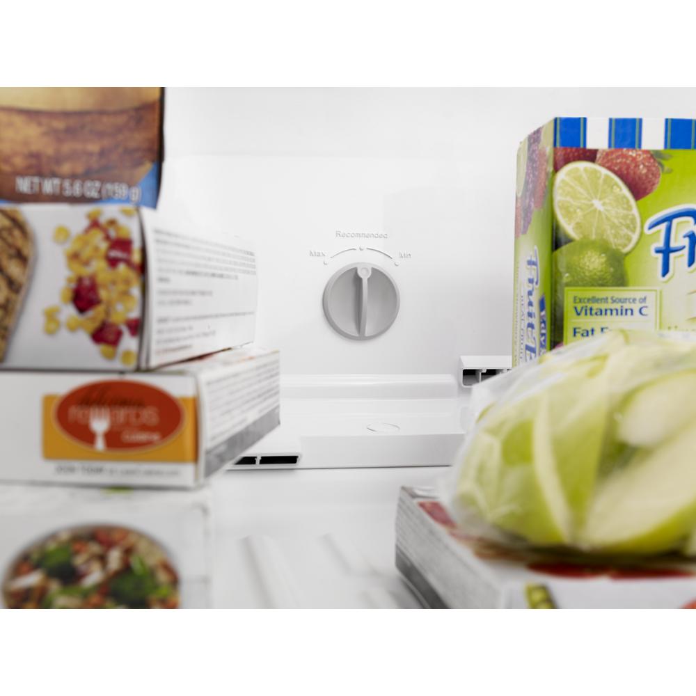 Close-up of temperature control dial inside a 28-inch Whirlpool refrigerator with frozen and fresh food packaging nearby